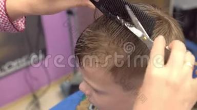 理发师用剪刀在男孩`头上剪刘海。 <strong>编剧</strong>`的双手特写，俯视图。